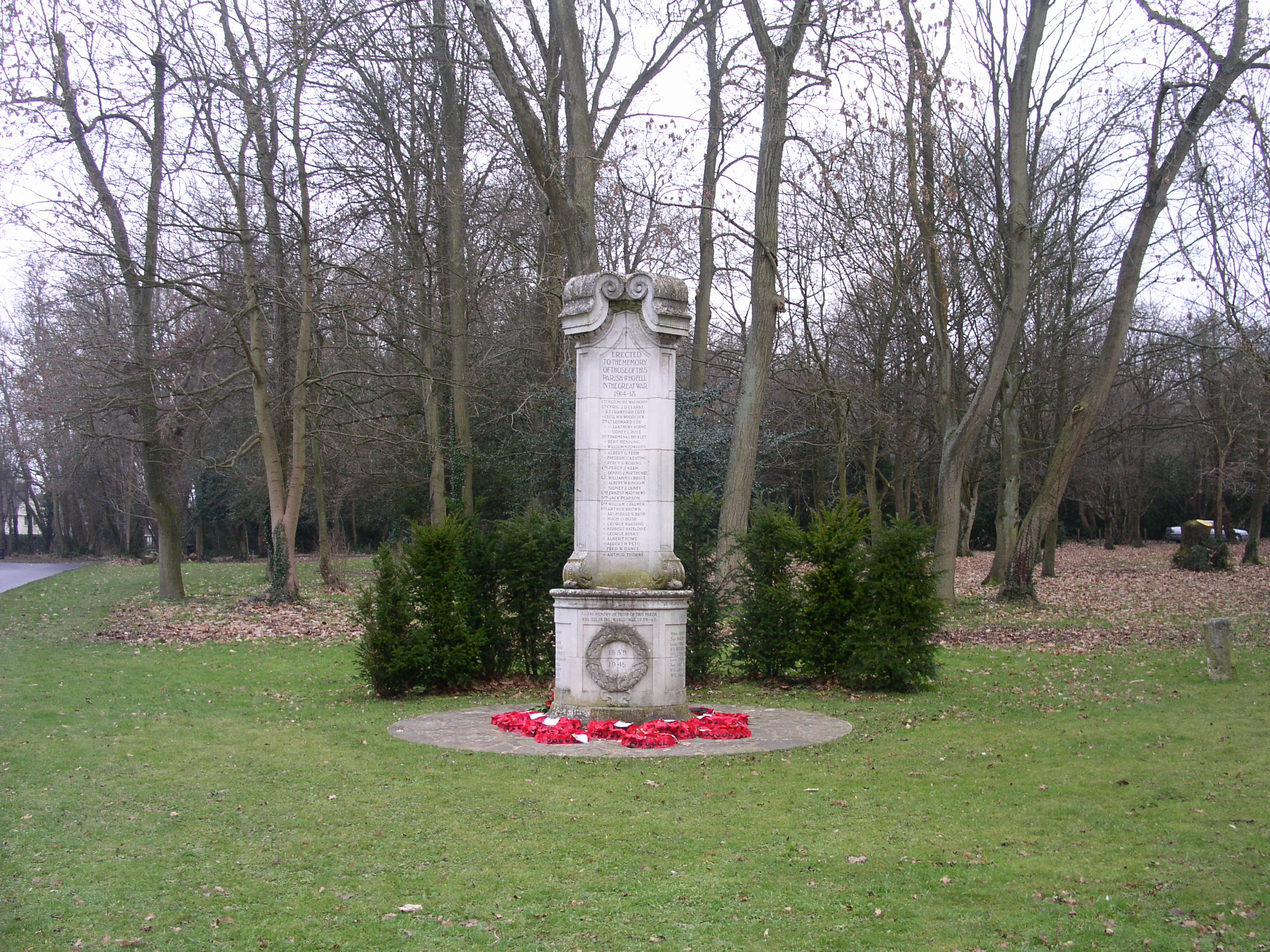 Photo of the Chesham Bois War Memorial with grass foreground and trees in the background